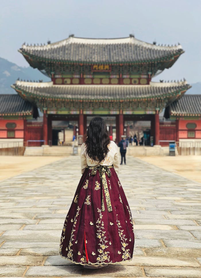 Woman in hanbok standing outside Gyeongbokgung Palace in Seoul, South Korea.
