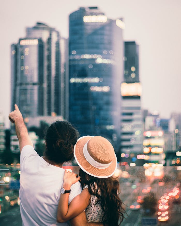 A young couple embraces while admiring the stunning Seoul skyline at dusk, creating a romantic atmosphere.